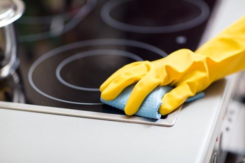 Kitchen cooktop being wiped clean during a deep cleaning